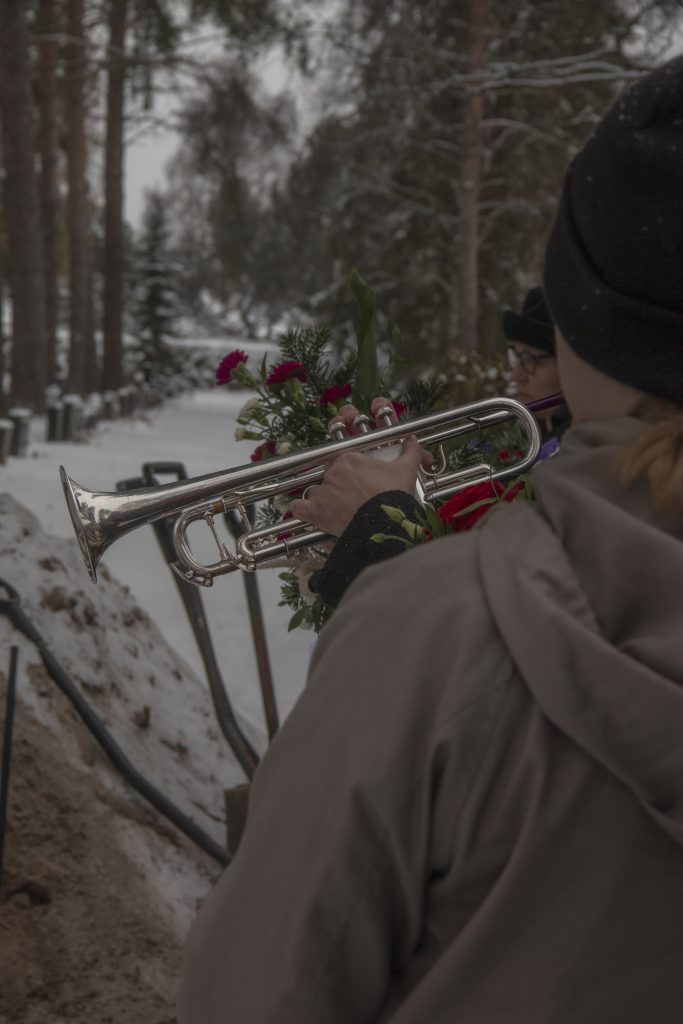 A fanfare is being played on a trumpet during a funeral ceremony